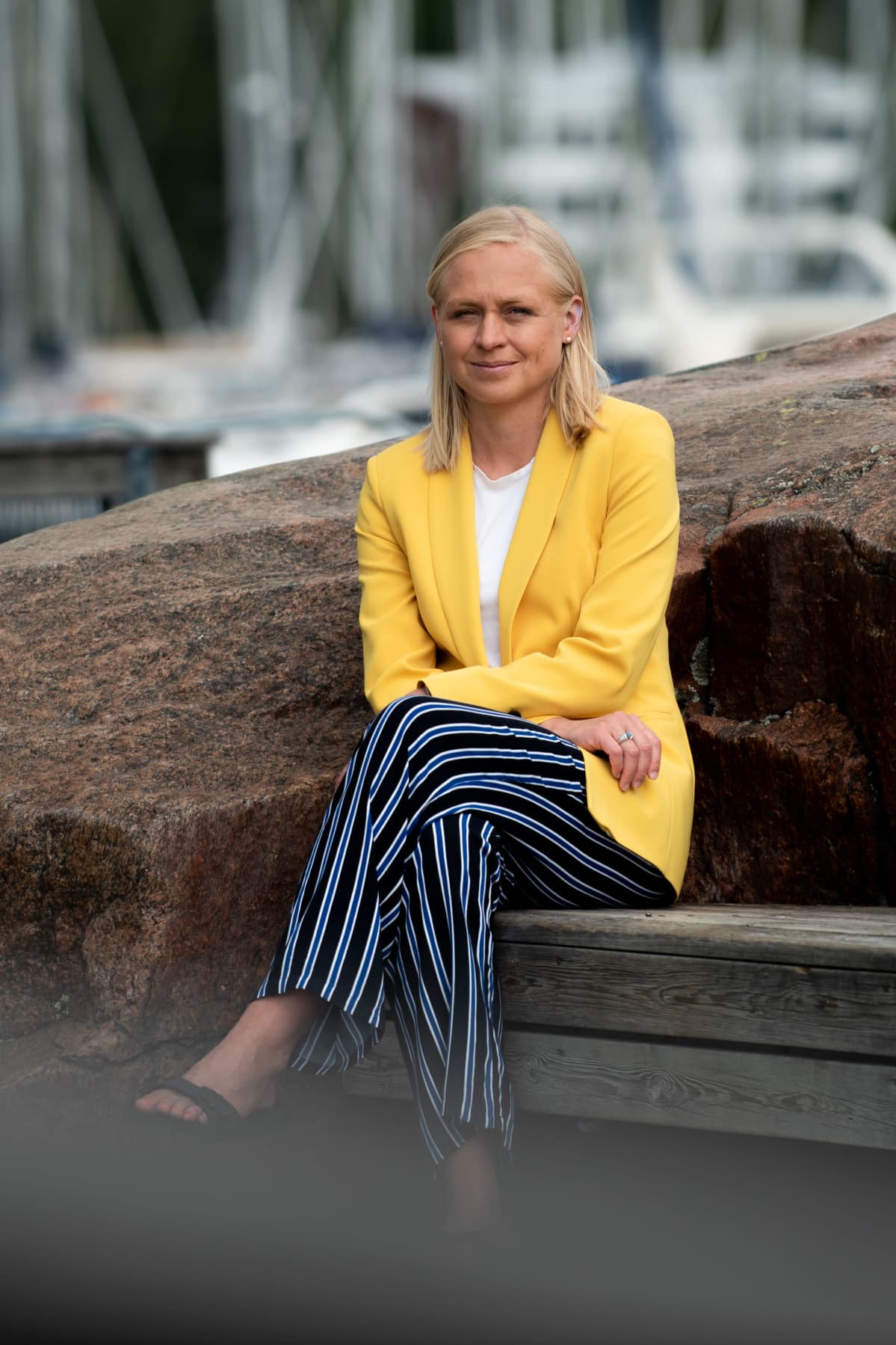 Elina Lepomäki istuu penkillä kallion kupeessa.
