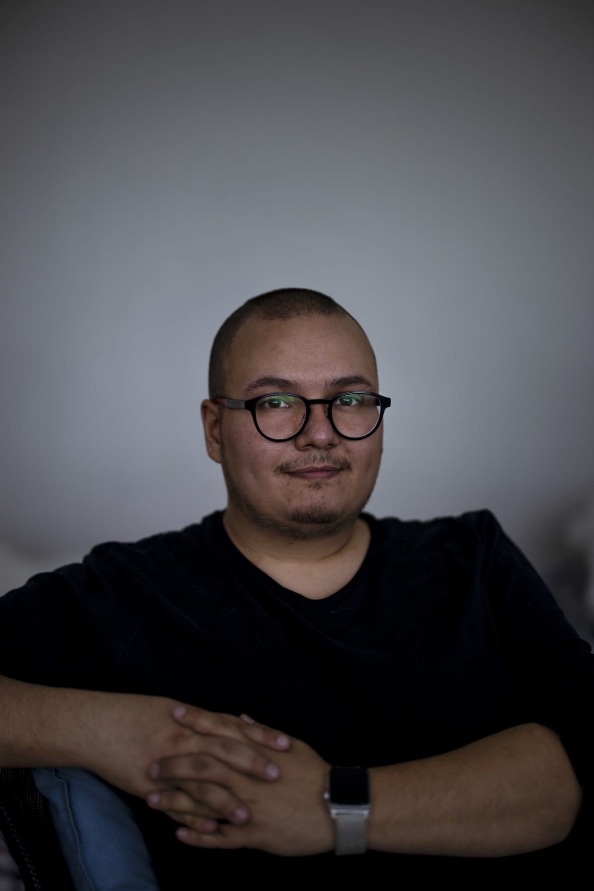 Lähikuva Benjamin Molinista hämärässä huoneessa valkoista seinää vasten.