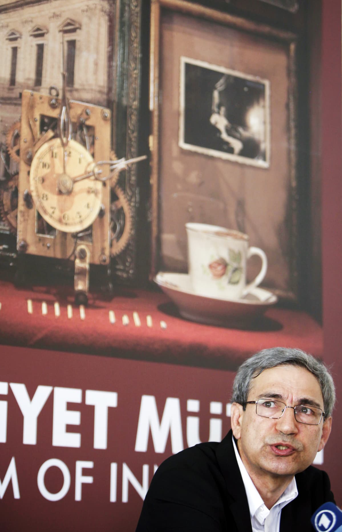 Orhan Pamuk museon mainosjulisteen edessä.