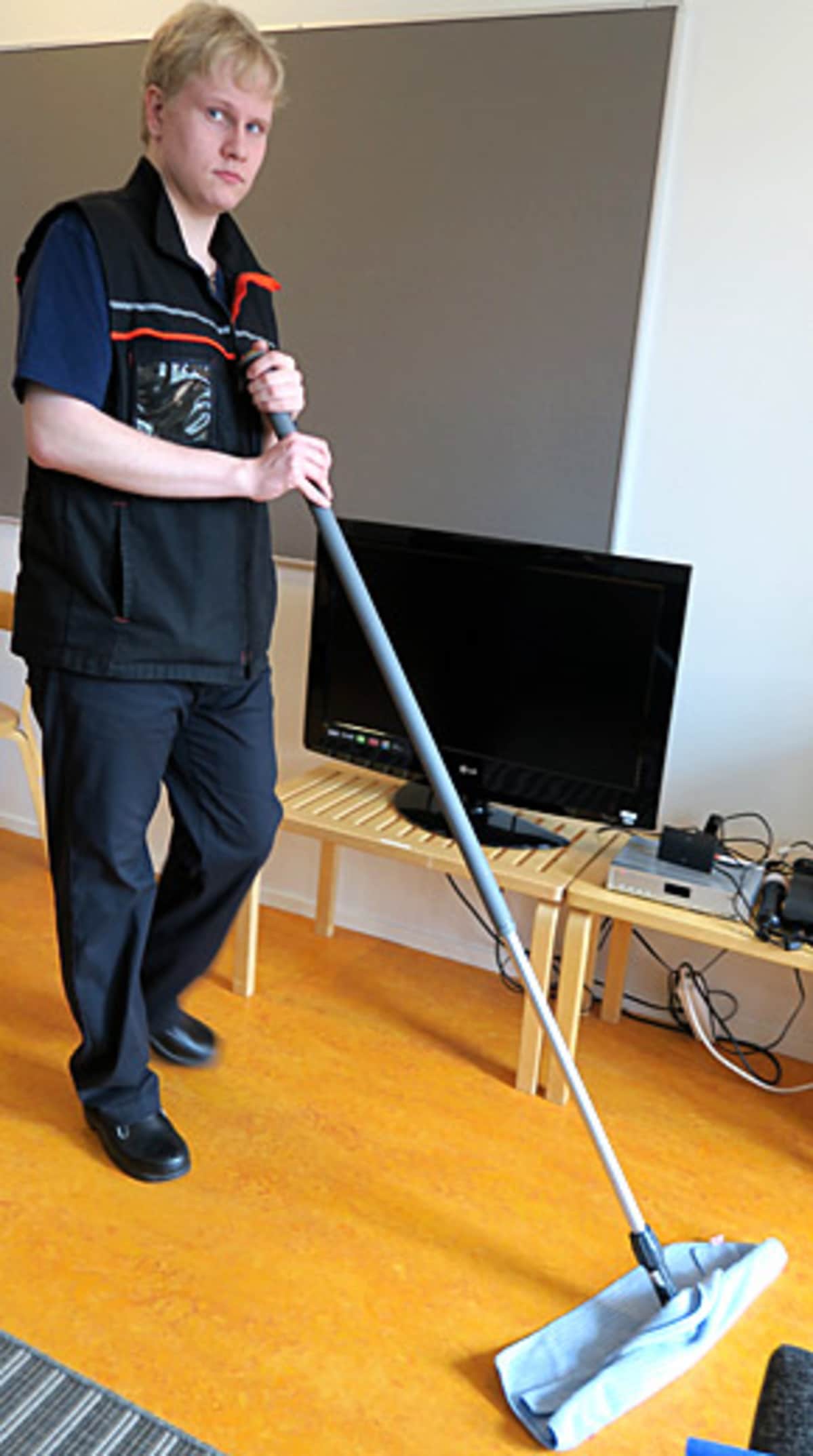 Nuori mies pyyhkii lattiaa lattiakuivaimella