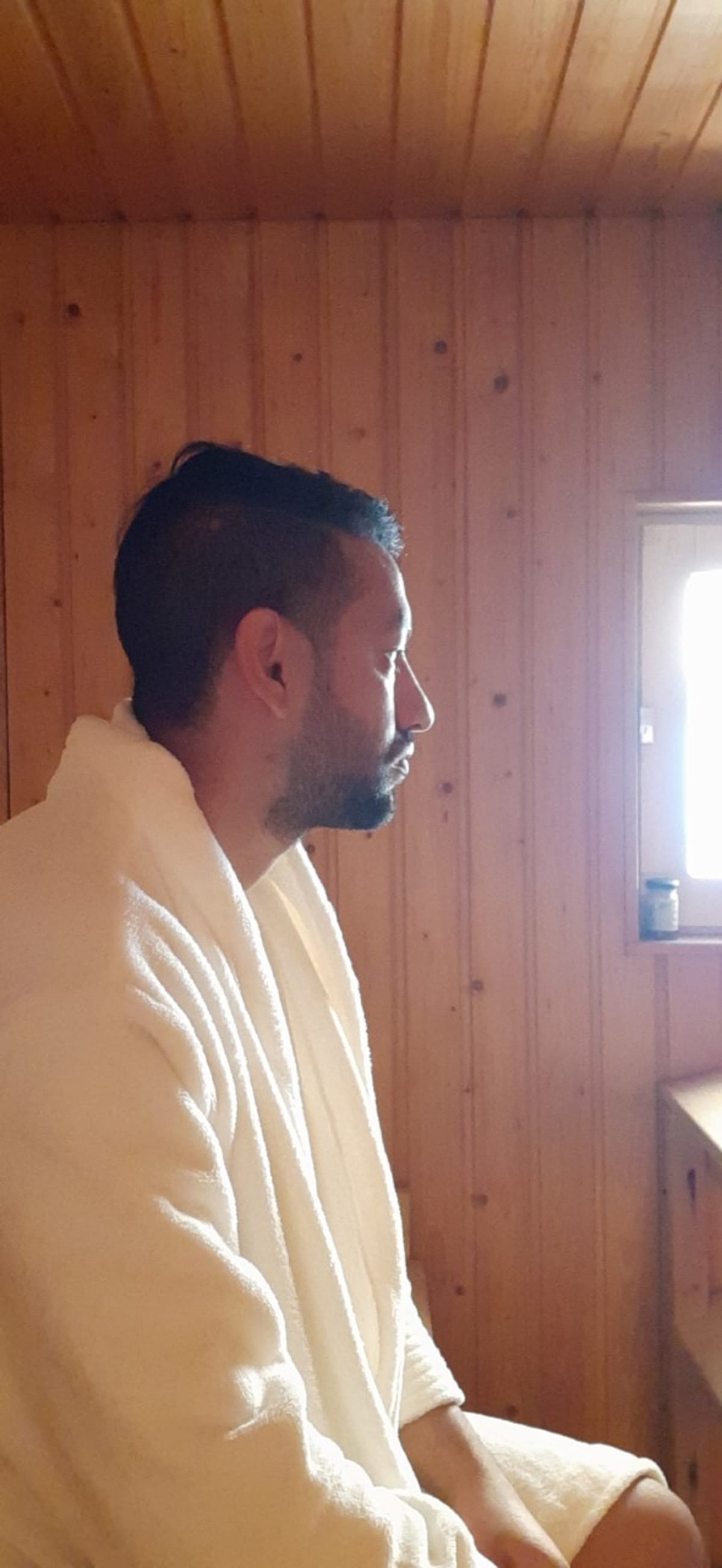 Pawan Aryal istuu saunatakki päällä saunassa.