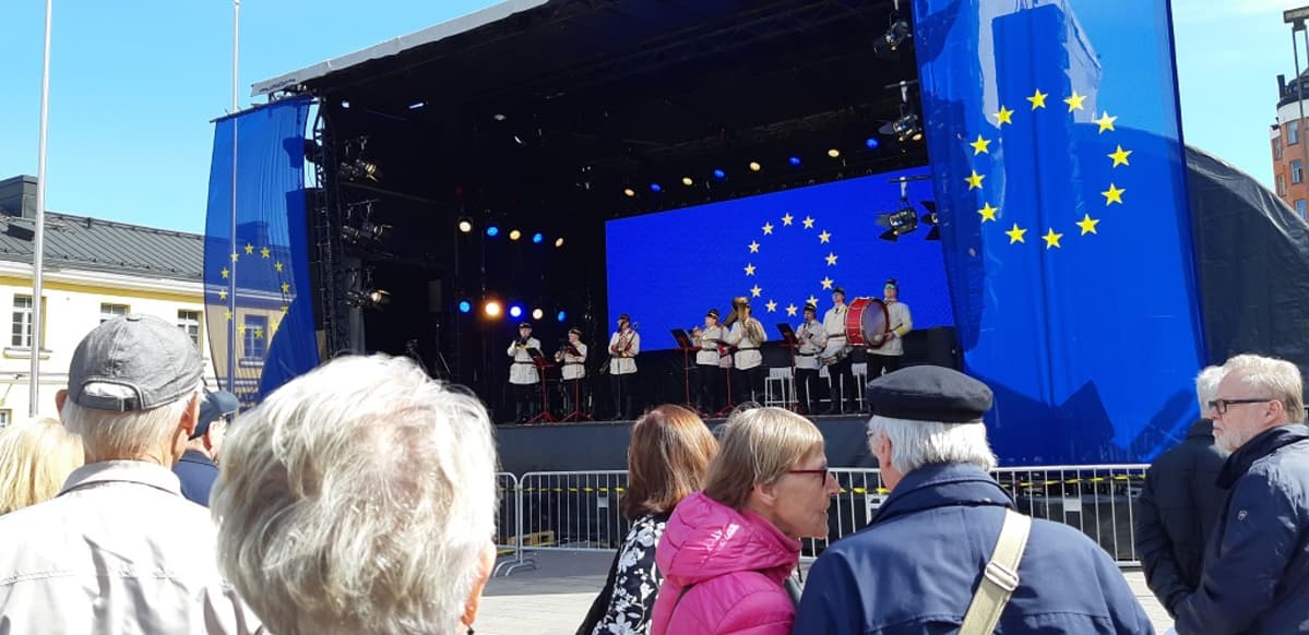 Torvisoittokunta Retuperän VPK soittamassa taustalla. Etulalla ihmisiä.