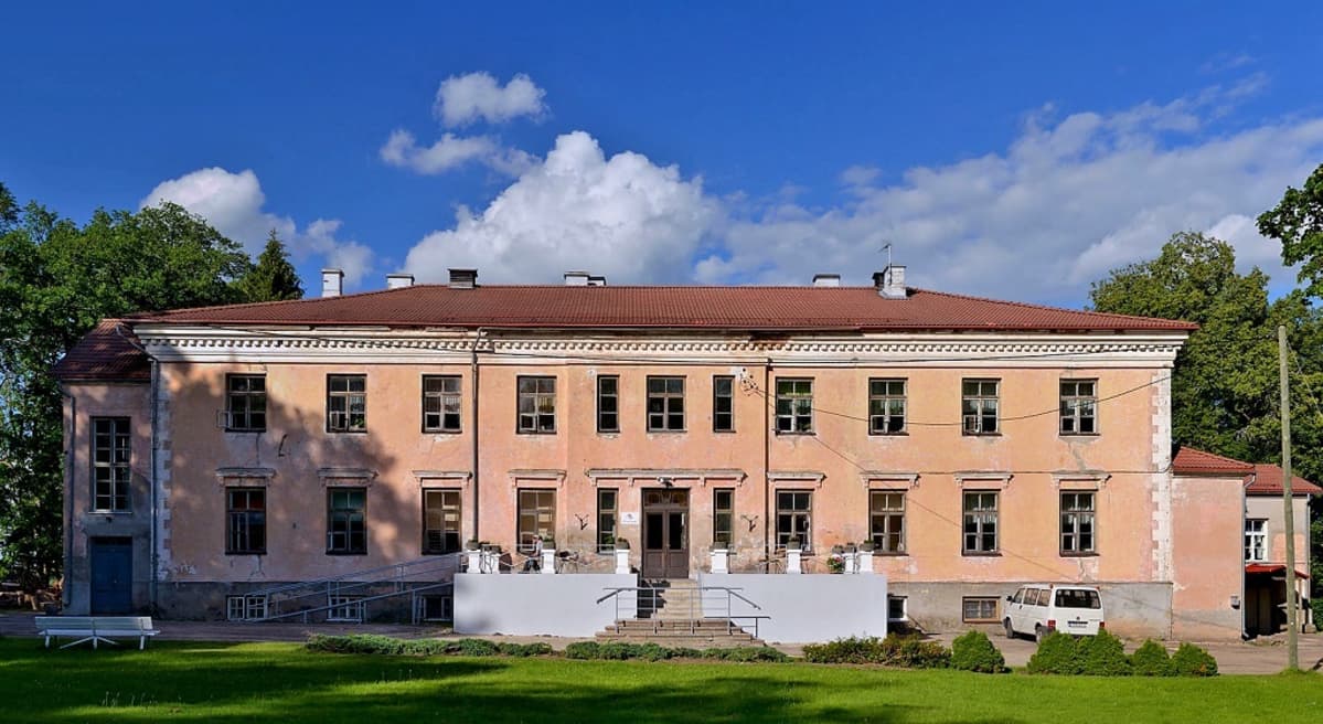 Lohenpunainen, kaksikerroksinen, hieman rapistunut rakennus.