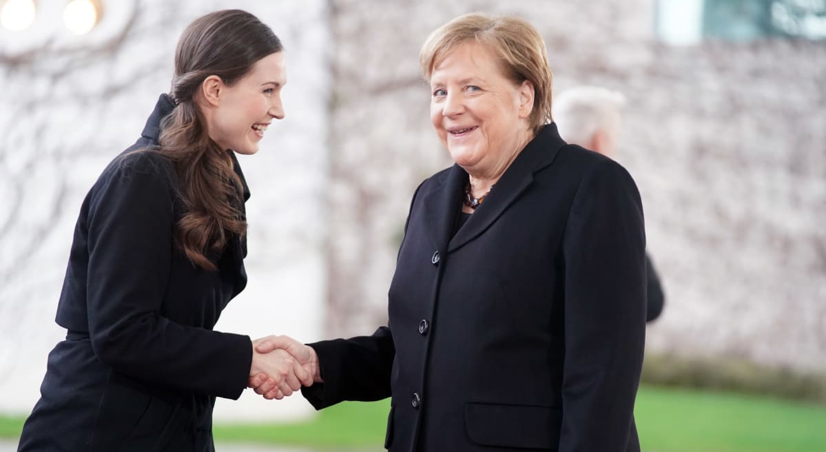 Sanna Marin ja Angela Merkel kättelevät hymyillen.