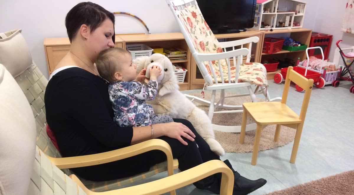 Äiti lapsi sylissään neuvolan odotushuoneessa.