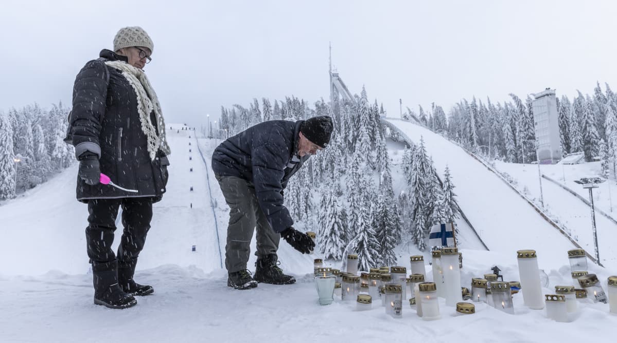 Mies ja nainen laittavan kynttilän Laajavuoressa Matti Nykäsen muistoksi.