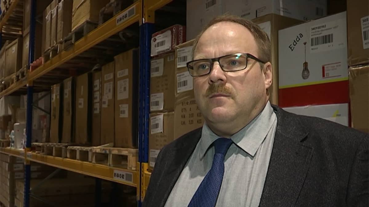 Veken Kalusteen uuden logistiikkakeskuksen hyllyt tavaraa pullollaan. Hyllyjen edustalla toimitusjohtaja Veijo Ranua.