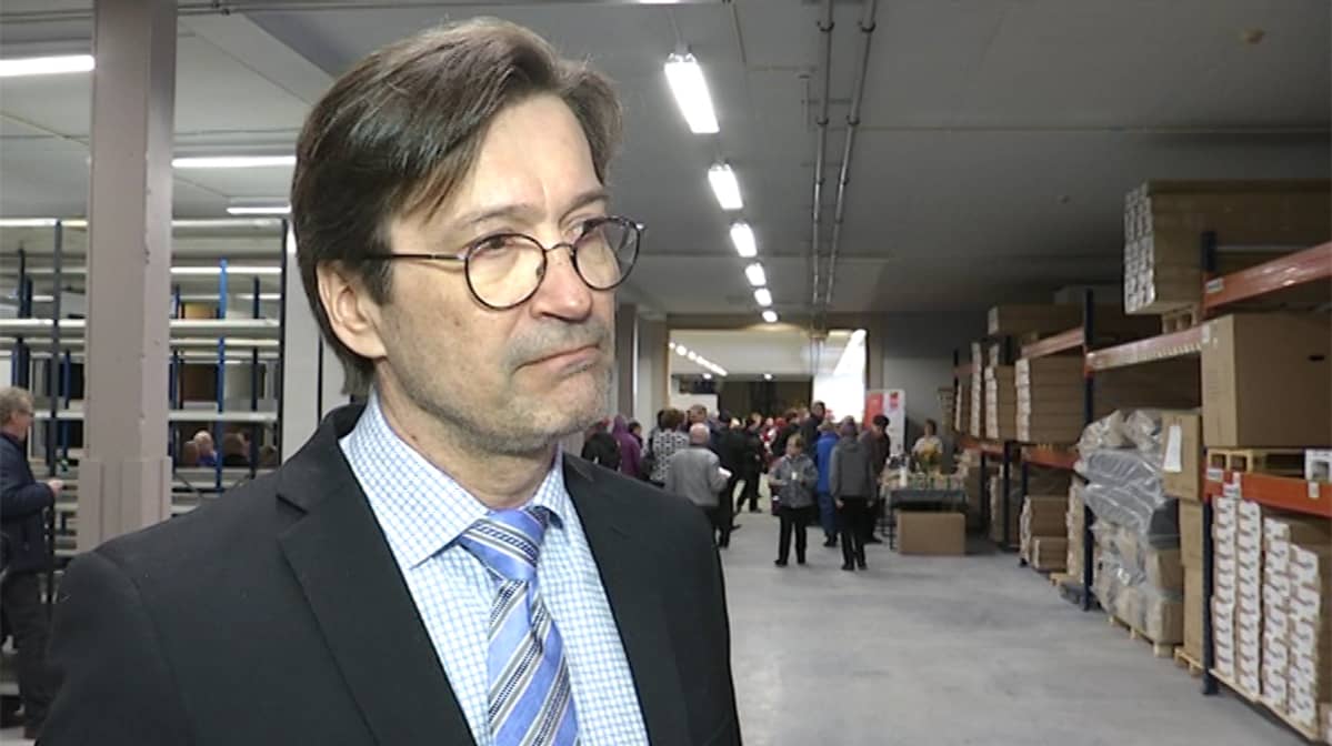 Lapin Yrittäjien toimitusjohtaja Pirkka Salo Veken Kalusteen uudessa logistiikkakeskuksessa. Kauempana taustalla avajaisia seuraavia ranualaisia ja hyllyttäin tavaraa.