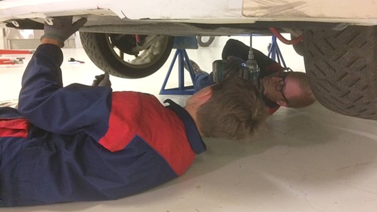 rallimekaanikkokoulutettavia auton alla vaihtamassa ralliauton pohjapanssaria