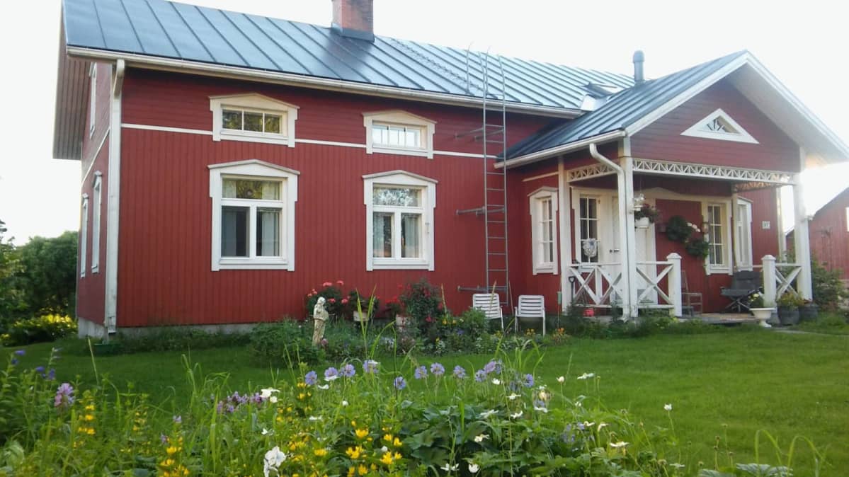 Punainen omakotitalo maalaismaisemassa.