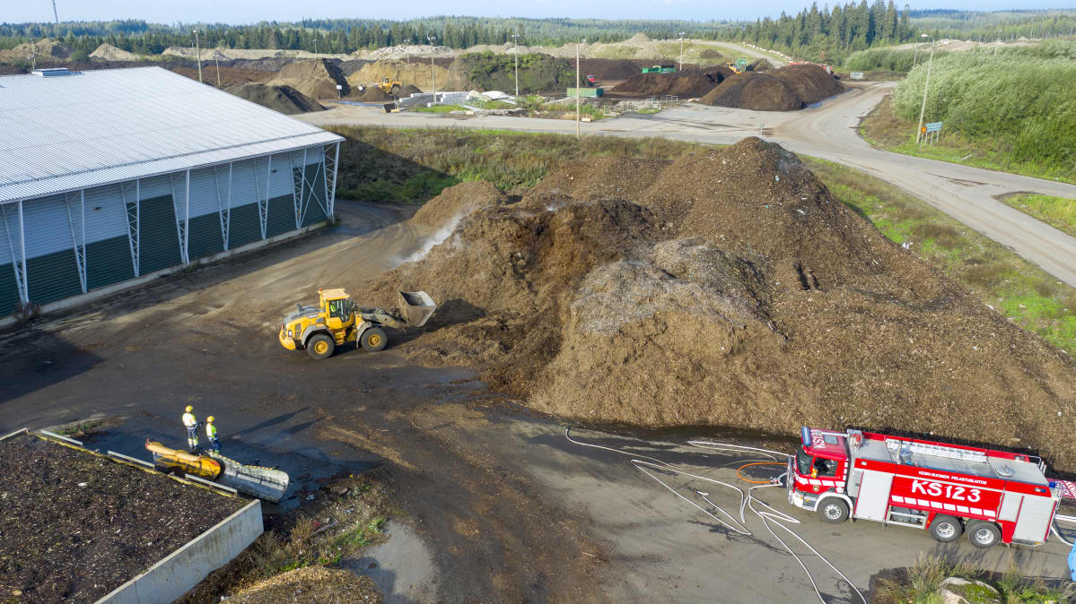 Hakekasa savuaa Mustankorkean jätteenkäsittelyasemalla, kuvassa myös paloauto.