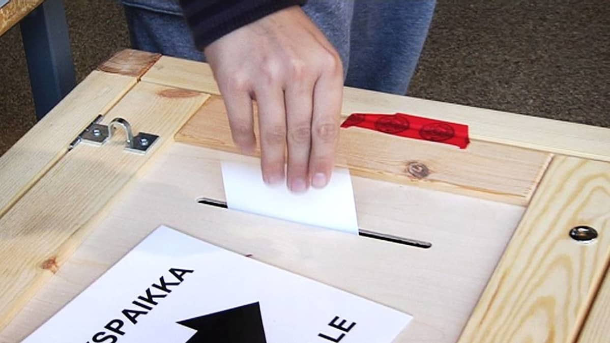 Äänestäjä tiputtaa vaalilipuketta uurnaan äänestyspaikalla.