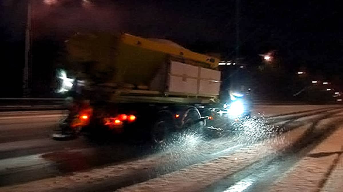 Kuorma-auto levittämässä suolaa maantielle.