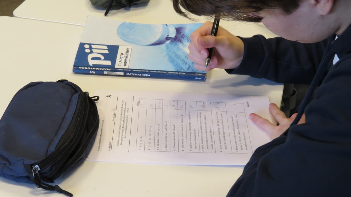Poika laskee matematiikan tehtävää.