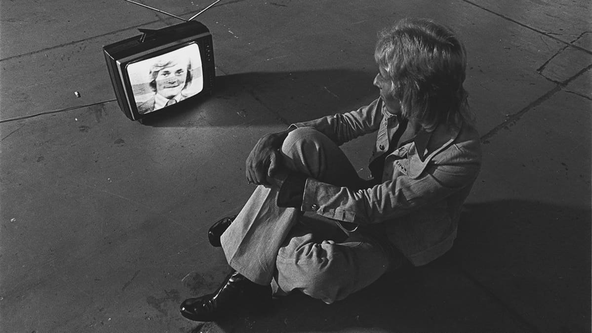 Timo T.A. Mikkonen televisioruudussa vuonna 1972. Televisiota katsoo tv-kriitikko Jukka Kajava.