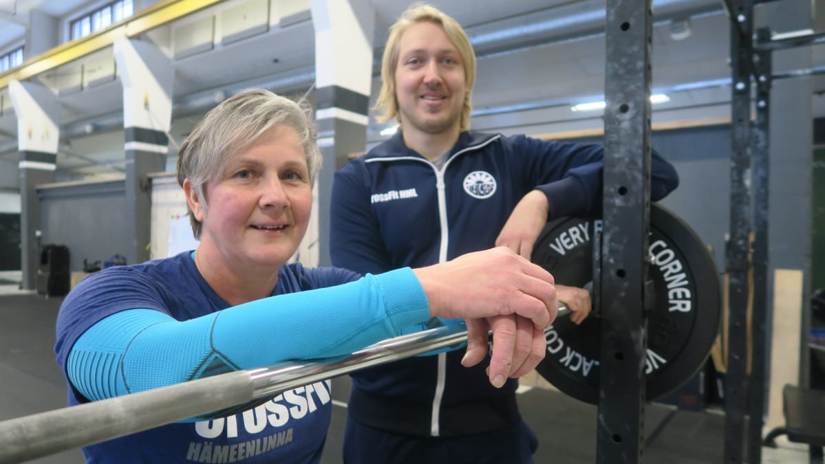 Nainen ja mies nojaavat painonnostotankoon crossfit-salilla