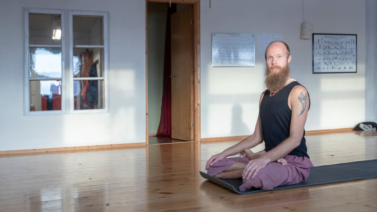 Joogaopettaja Atmananda Puri istuu joogamatolla.