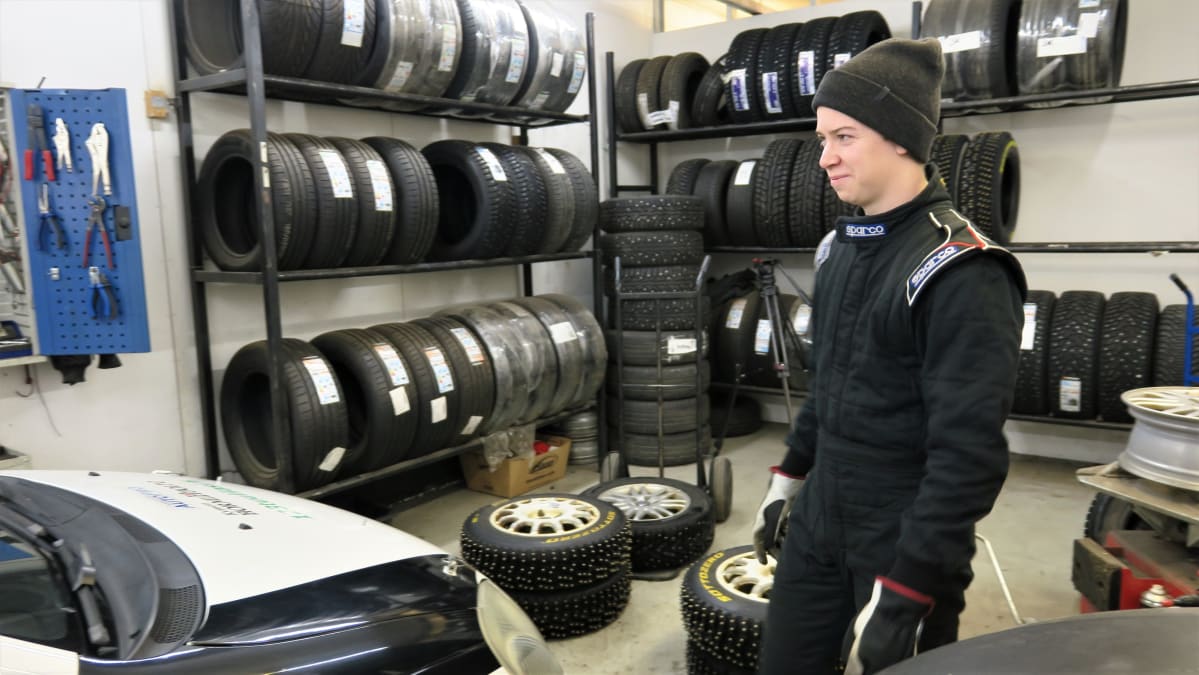 Rallikuski Niklas Heino myhäilee autohallissa.