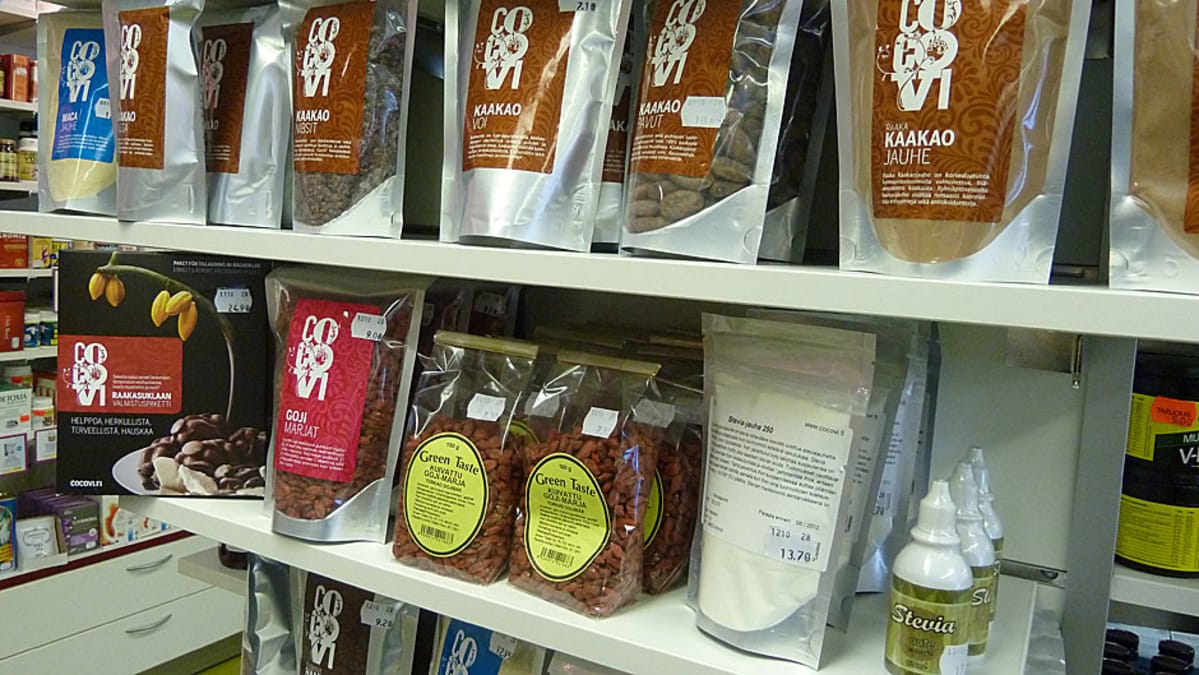 Superfoodeja luontaistuotekaupan hyllyllä, esimerkiksi kaakaopavut, kaakaovoi, goji-marjat ja maca-jauhe.