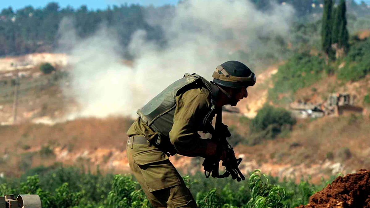 Israelilaissotilas suojautuu tulitukselta Hizbollahin hyökättyä israelilaissaattuetta vastaan.