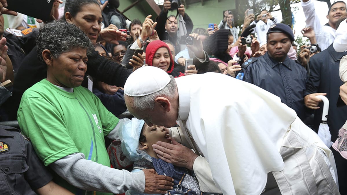 Paavi Franciscus siunaa lapsen vieraillessaan Varginhan favelassa Rio de Janeirossa.