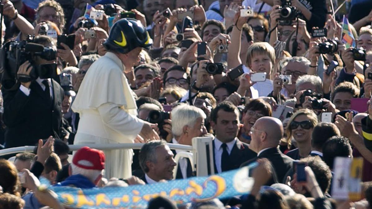 Paavi Franciscus käyttää palomiehen kypärää tavatessaan kansaa Pyhän Pietarin aukiolla Vatikaanissa.