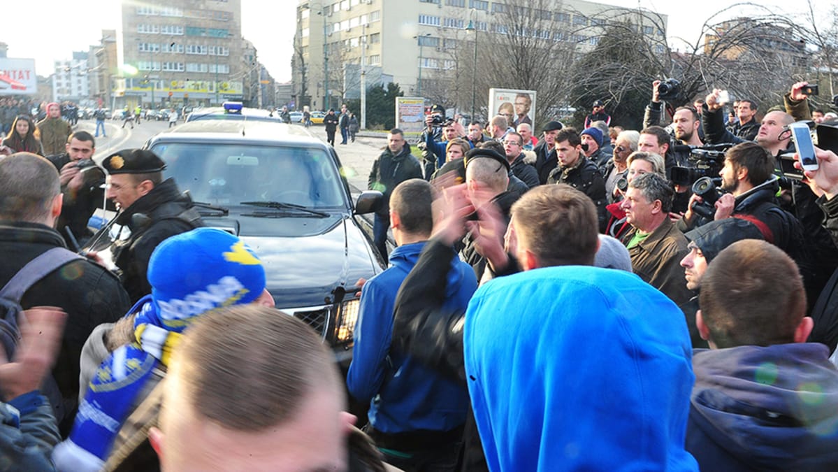 Ihmiset tukkivat poliisiautojen kulun kadulla.