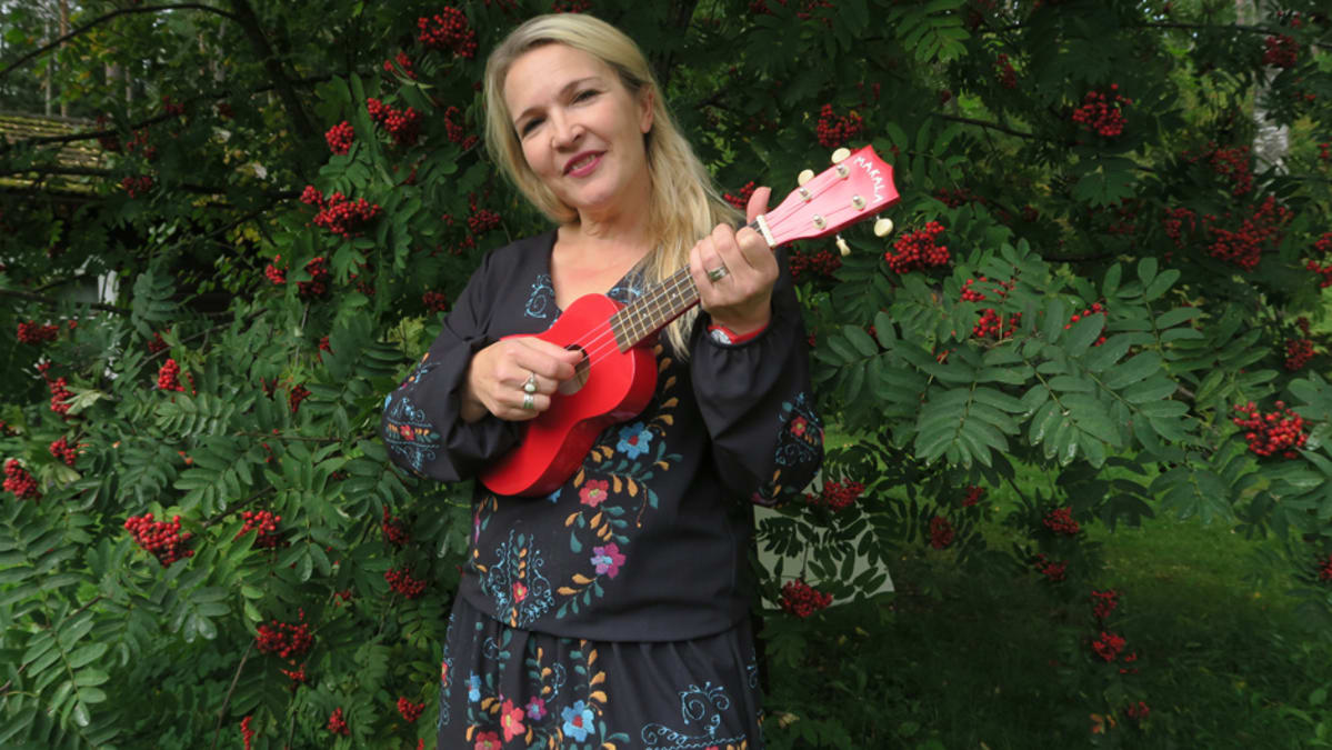 Mari Kaasinen ja ukulele pihapihlajan edessä.