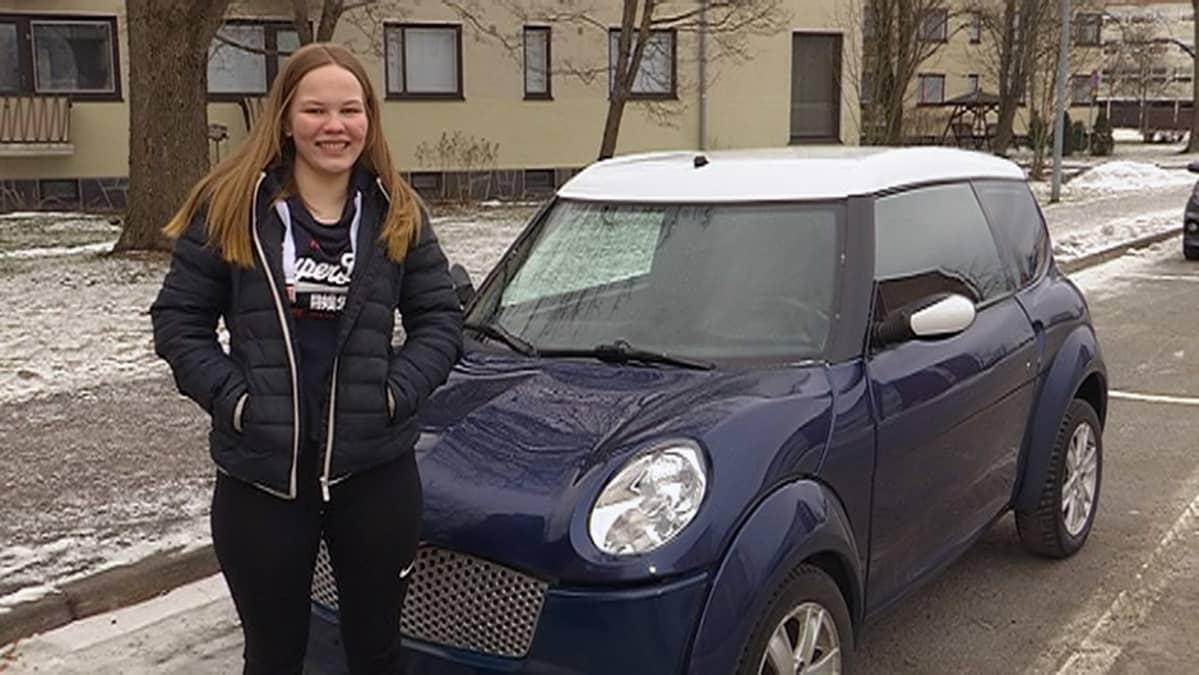 Anni Mäntyvaara seisoo mopoauton vierellä