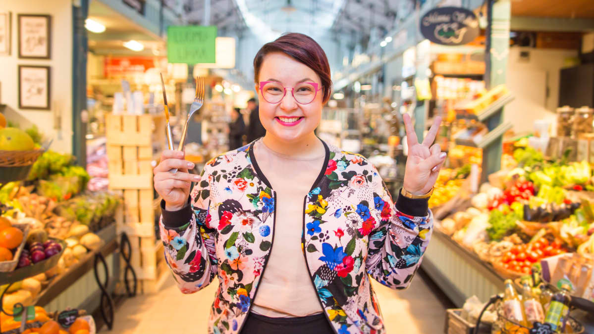 Ruokalähettiläs Emmi Nuorgam poseeraa haarukka ja veitsi kädessä Tampereen kauppahallissa.