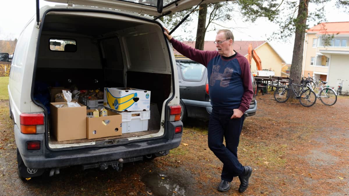 Mies katsoo pakettiauton takaosassa olevia ruokatarpeita.