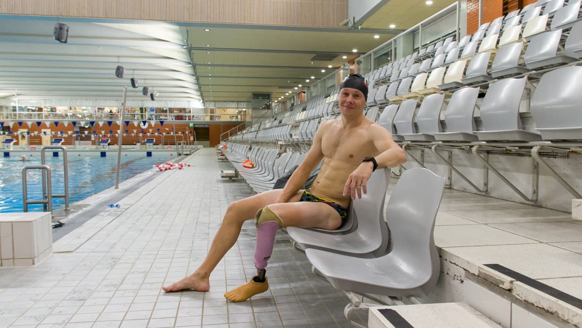 Paratriathlonisti Jussi Lotvonen istuu Raksilan uimahallin katsomossa.