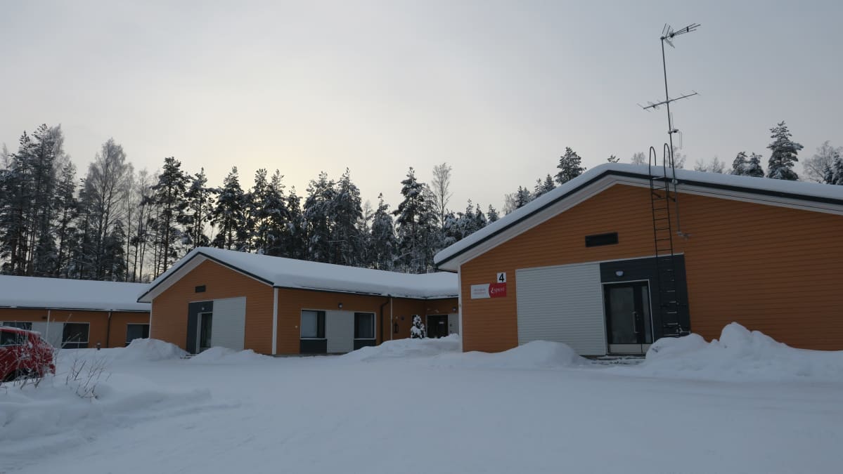 Kolme oranssiksi maalattua hoivakotirakennusta rinnan lumisella pihalla.