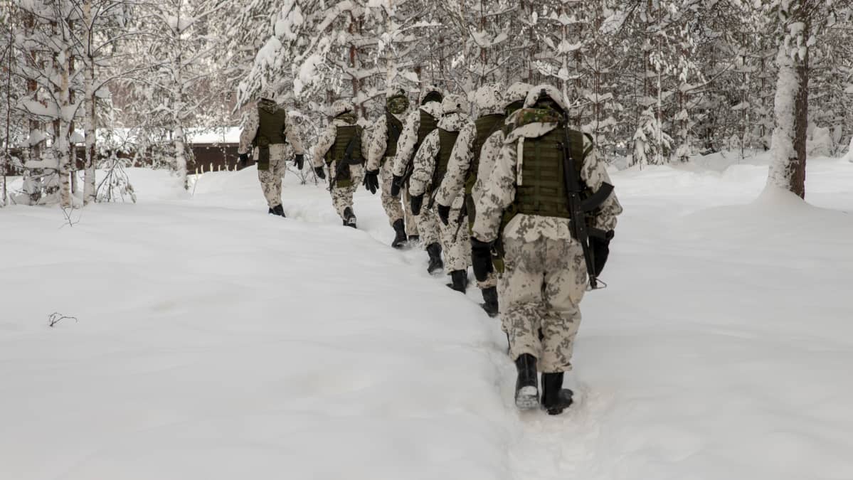 Alokkaat kulkevat jonossa lumisessa metsässä polkua pitkin aseet olalla