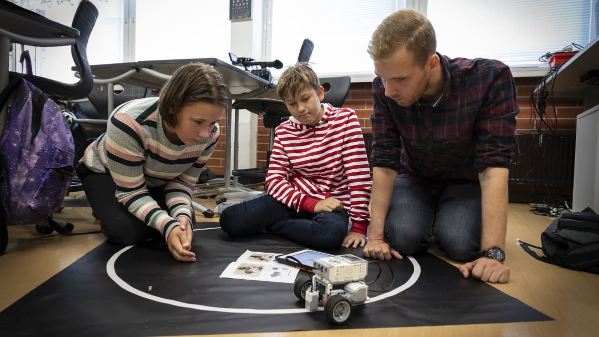 Koululaiset ja opettaja seuraavat robotin liikkumista koululuokassa.