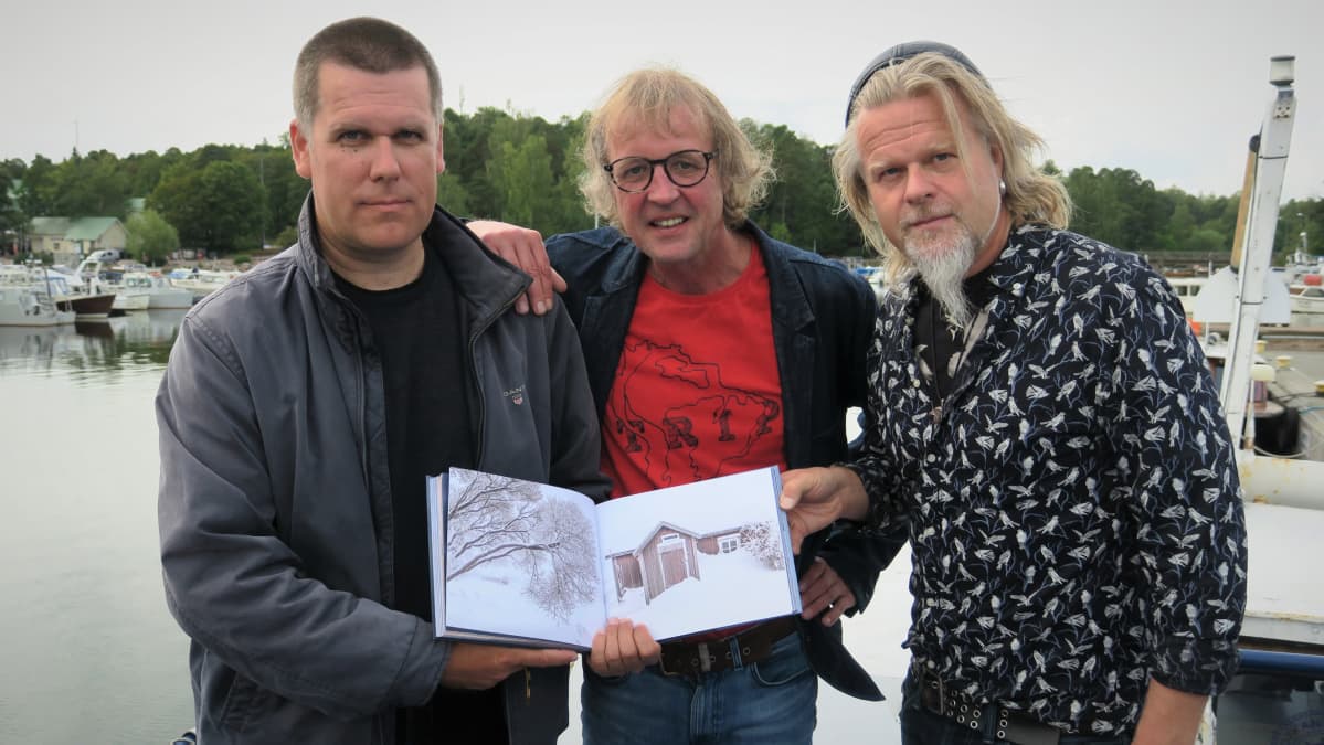 Mika Rokka, Ville Vanhala ja Juha Metso poseeraavat Murtuvan aallon harjalla -kirjan kanssa.