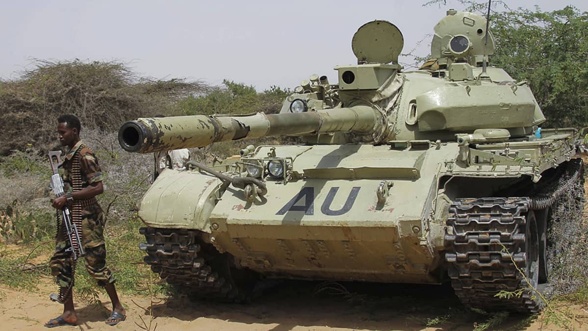 Somalian hallituksen sotilas kävelee AMISOM-rauhanturvaoperaation panssarivaunun vierellä.