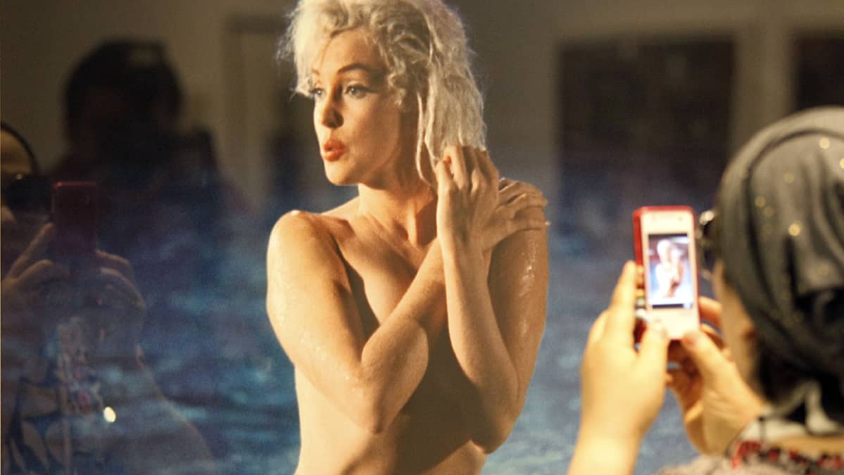 Näyttelyvieras ottaa älypuhelimellaan kuvaa Marilyn Monroen alastonkuvasta.