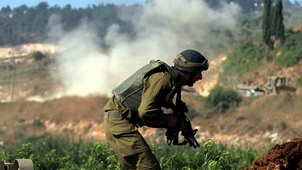 Israelilaissotilas suojautuu tulitukselta Hizbollahin hyökättyä israelilaissaattuetta vastaan.