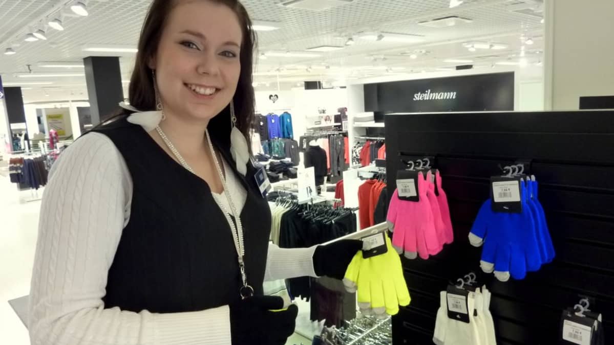 Myyjä Niina Parkkonen esittelee neonvärisiä kosketusnäyttösormikkaita.