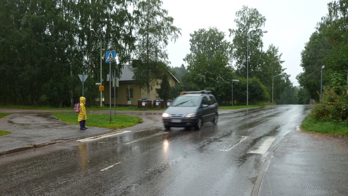 Huhtimonkadulla lapsi odottaa pääsyä suojatien yli, auto tulee lujaa.