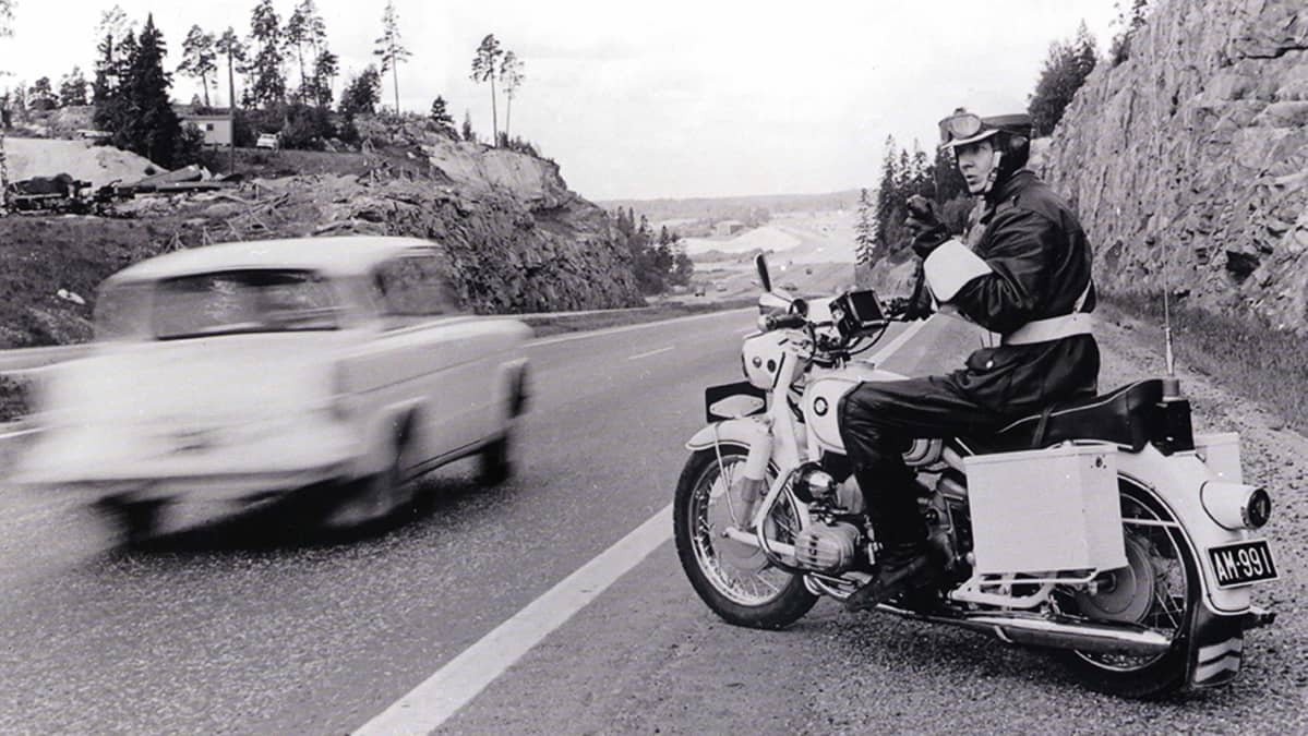 Moottoripyöräpoliisi valvomassa liikennettä maantien varressa.