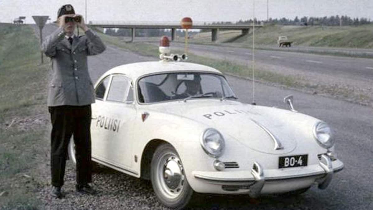 Poliisi kiikaroi autonsa vieressä maantien laidassa.