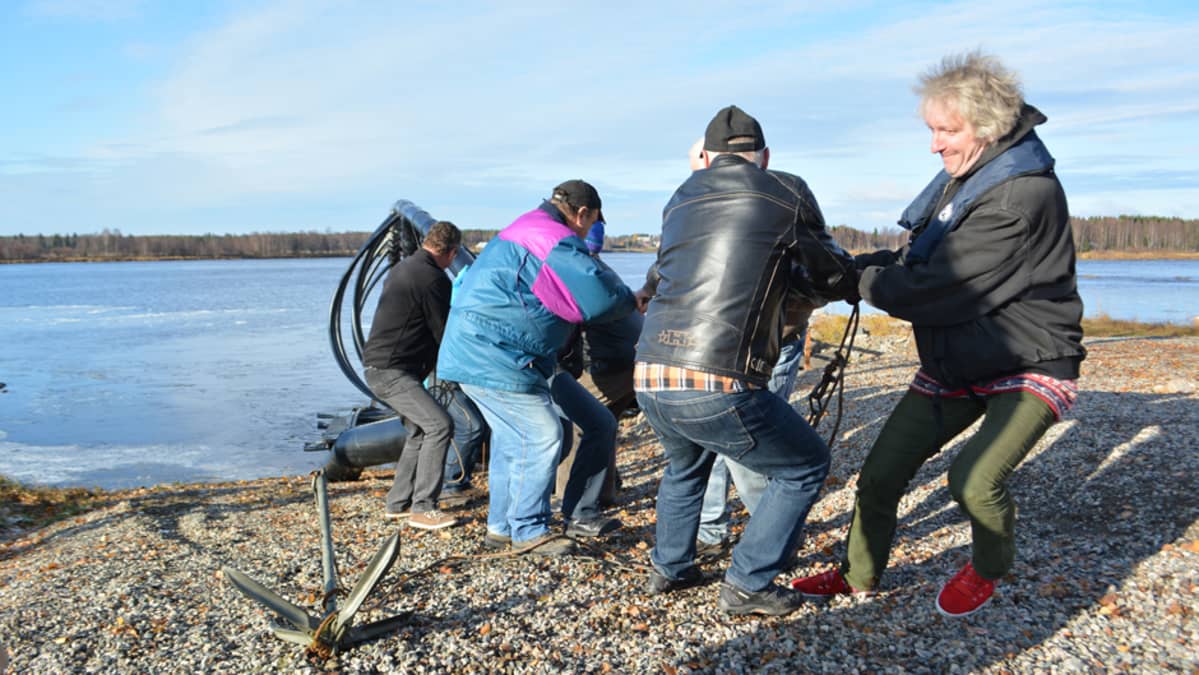 Miehet kiskovat siian muotoista lauttaa rannalle