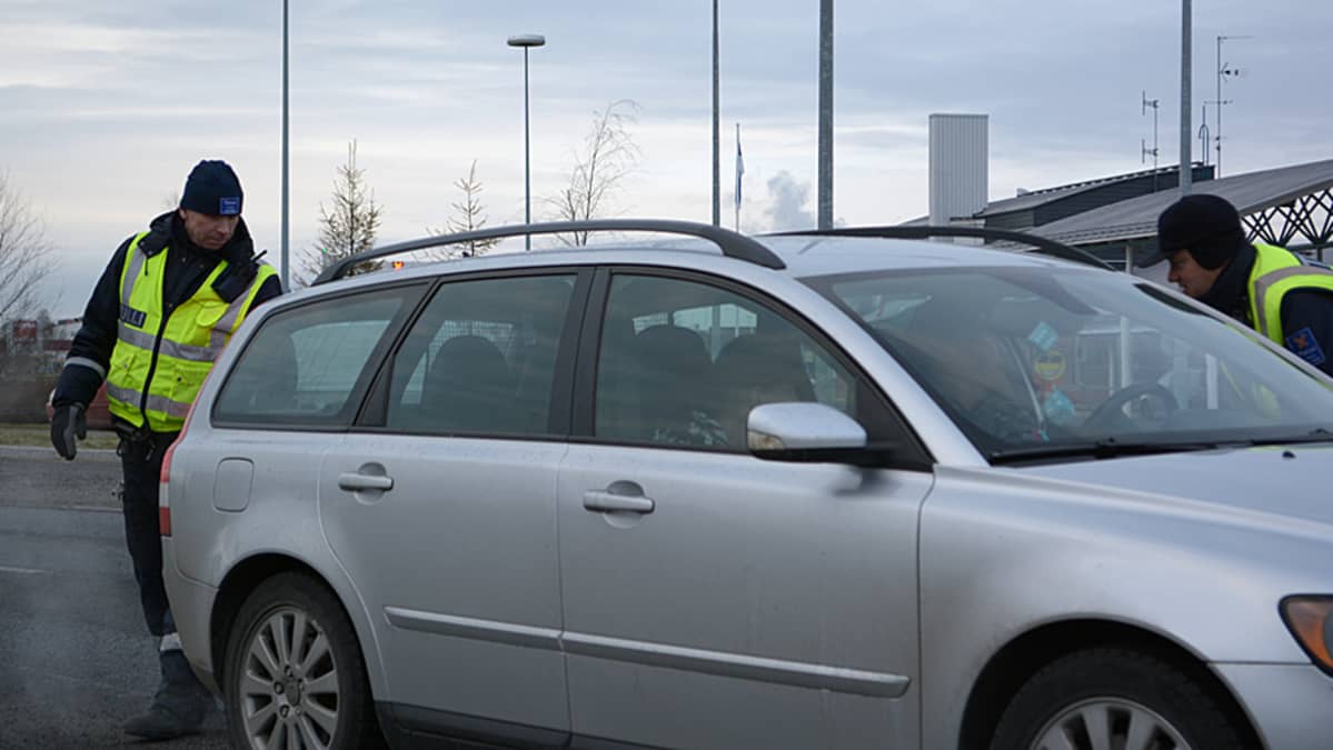 Tullimiehet tarkastavat henkilöautoa.