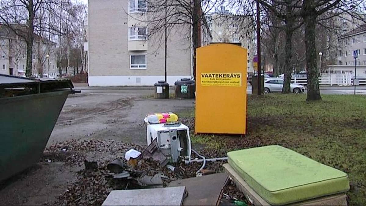 Patjoja, pesukone ja jätteitä kierrätyspisteen ympäristössä