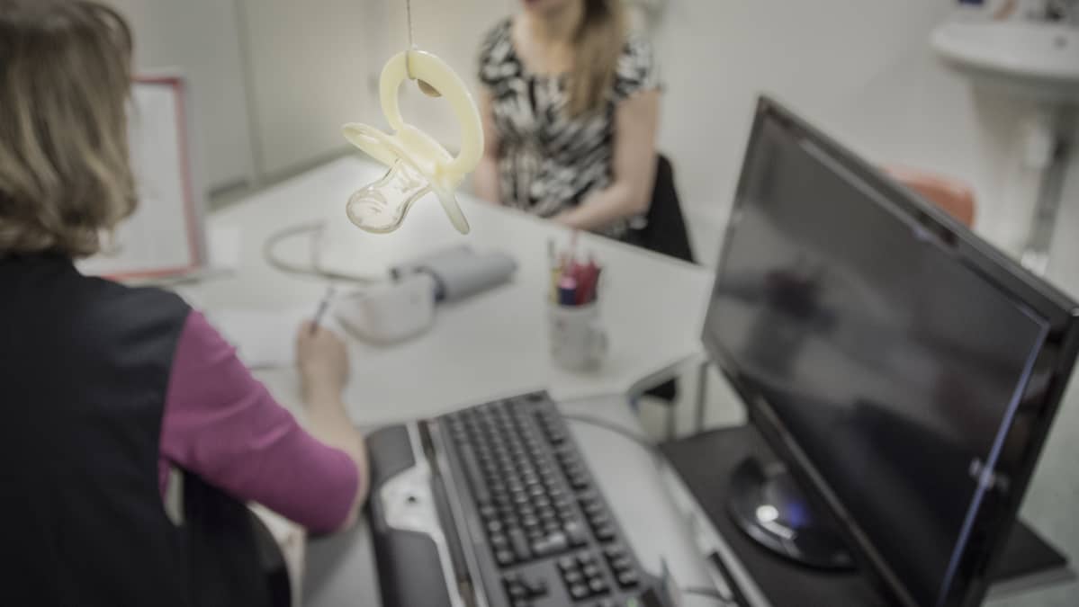 Terveydenhoitaja juttelee odottavan äidin kanssa neuvolan vastaanottohuoneessa.