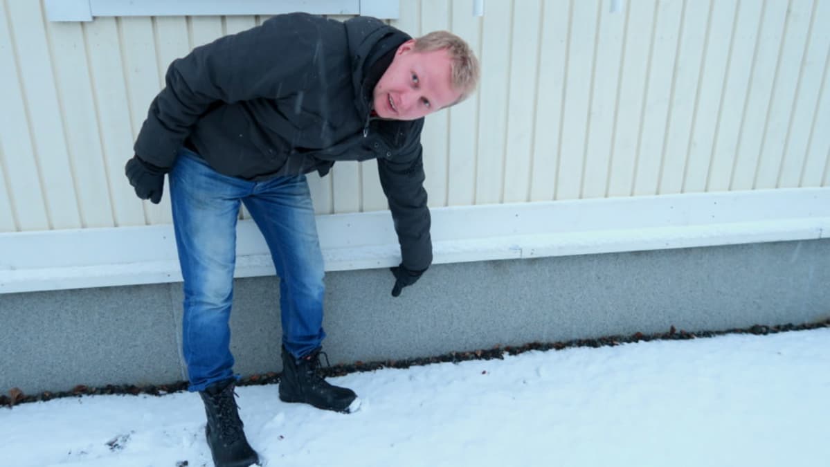 Mies osoittaa talon ulkovuorauksen tuuletusrakoa