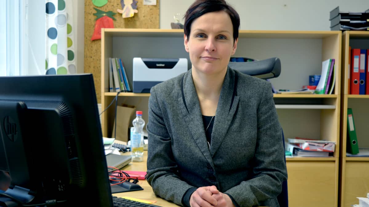 Tiina Veijola istuu toimistossaan ja katsoo kameraan.