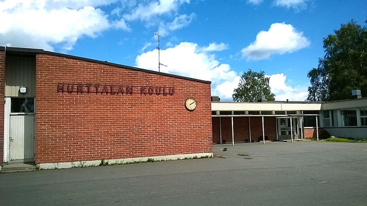 Punatiilinen vanha koulu ja sen pihaa.